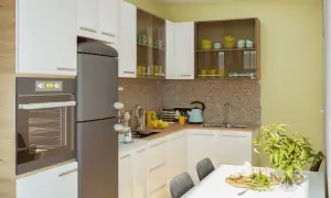 Nowoczesna kuchnia w projekcie mieszkania 70m2. Białe szafki, szary lodówka, żółte akcenty i mozaika na ścianie.