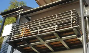 Nowoczesne rodzaje balkonów: stalowa konstrukcja z drewnianym tarasem i metalową balustradą.