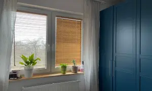 Eleganckie żaluzje bambusowe aranżacje okna, tworzące przytulną atmosferę. Obok niebieska szafa.