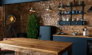 Drewniany stół i ceglana ściana tworzą przytulne loftowe wnętrza inspiracje. Widać lodówkę retro, industrialną lampę i wiszące lampy.