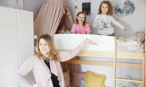 Uroczy mały pokój dla rodzeństwa w bloku. Dwie dziewczynki bawią się na łóżku piętrowym, a mama prezentuje przestrzeń.