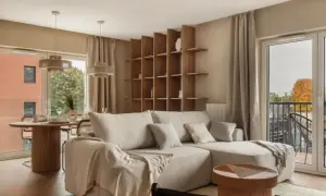 Przytulny salon z beżową kanapą, drewnianym regałem i okrągłym stołem. Piękne wnętrza inspiracje dla Twojego domu.