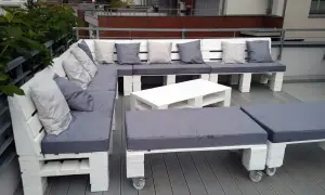 Narożna sofa i stolik kawowy z palet, pomysły na meble z palet. Szare poduszki dodają przytulności.