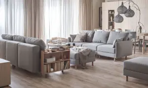 Jasne wnętrza inspiracje: przytulny salon z szarą sofą, drewnianymi meblami i zasłonami.