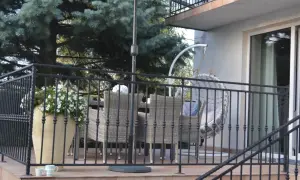 Taras nad garażem inspiracje: rattanowe meble, wiszący fotel i bujna zieleń tworzą przytulną przestrzeń do relaksu.