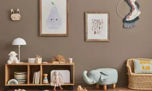 Przytulny pokój zabaw dla dzieci w domu. Na ścianie wiszą obrazki z gruszką i napisem "Small steps every day". Na półce stoi lampka, pluszowa owieczka i książki. Obok siedzi lalka-króliczek. Na podłodze leżą drewniane klocki i puf w kształcie słonia.