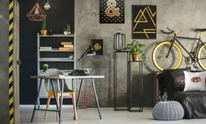 Nowoczesne ściany w pokoju młodzieżowym z betonową fakturą, ozdobione złotymi grafikami i czarnymi akcentami. Styl industrialny i rockowy.