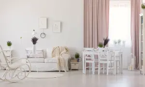 Jasny salon w stylu prowansalskim. Biała kanapa, fotel bujany, stół z krzesłami i lawenda tworzą przytulną atmosferę.