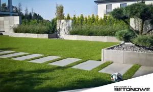 Nowoczesne płyty betonowe w ogrodzie tworzą ścieżkę przez trawnik. Aranżacje z betonowych elementów podkreślają piękno zieleni.