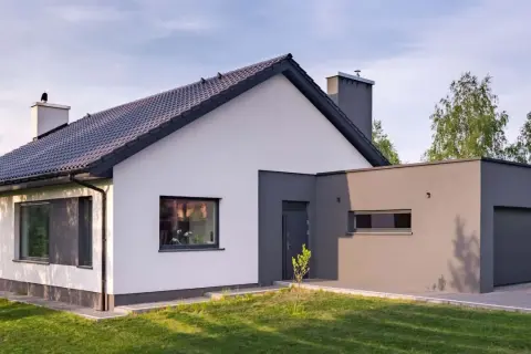 Nowoczesny dom z białymi i grafitowymi ścianami, idealnie wpisujący się w najmodniejsze kolory elewacji. Dachówka i okna w ciemnym odcieniu.
