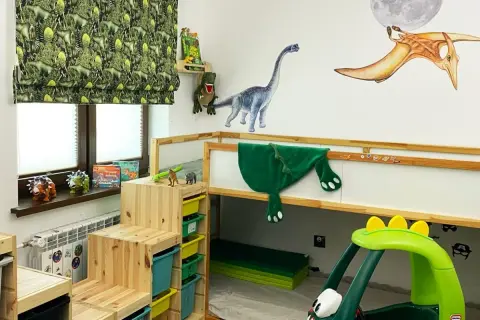 Pokój dla chłopca 7 lat inspiracje: dinozaury na ścianach, zasłonach i zabawkach. Drewniane schodki do łóżka piętrowego i zielony samochodzik.