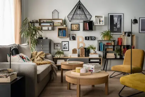 Nowoczesne półki na ścianę inspiracje: salon z szarą kanapą, drewnianymi stolikami i żółtym fotelem.