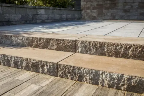 Solidne schody z bloczków betonowych prowadzą na taras. Kamienne stopnie z chropowatą fakturą.
