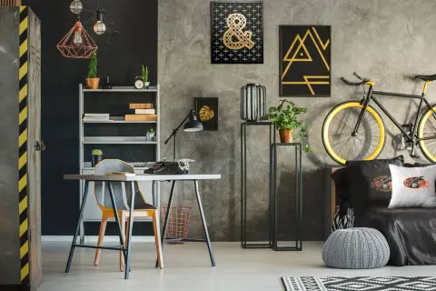 Nowoczesne ściany w pokoju młodzieżowym z betonową fakturą, ozdobione złotymi grafikami i czarnymi akcentami. Styl industrialny i rockowy.