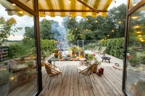Przytulny projekt domu z tarasem, gdzie grill i kwiaty tworzą atmosferę letniego wieczoru.