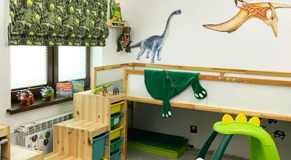 Pokój dla chłopca 7 lat inspiracje: dinozaury na ścianach, zasłonach i zabawkach. Drewniane schodki do łóżka piętrowego i zielony samochodzik.