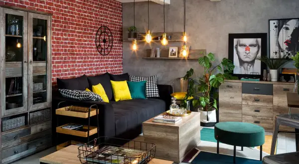 Męski pokój inspiracje: loftowy salon z ceglaną ścianą, czarną kanapą, drewnianymi meblami i industrialnymi lampami.