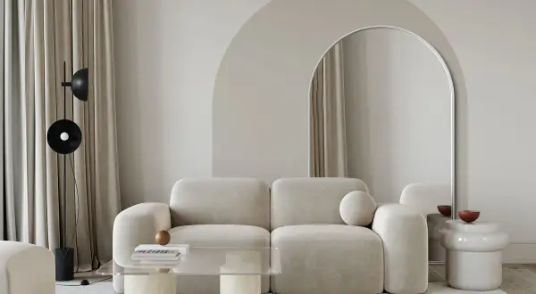Nowoczesny salon z beżową kanapą i łukiem nad lustrem. Świetny pomysł na łuk w domu, który optycznie powiększa przestrzeń.