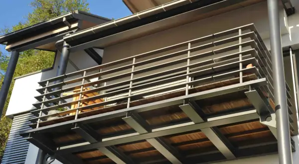Nowoczesne rodzaje balkonów: stalowa konstrukcja z drewnianym tarasem i metalową balustradą.