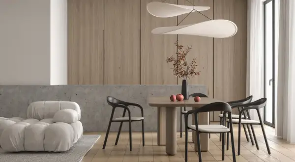 Piękne nowoczesne wnętrza: jadalnia z drewnianym stołem, czarnymi krzesłami i designerskimi lampami. Obok wygodna, biała sofa.
