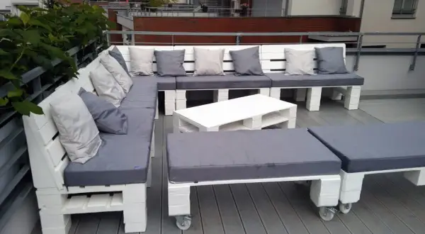 Narożna sofa i stolik kawowy z palet, pomysły na meble z palet. Szare poduszki dodają przytulności.