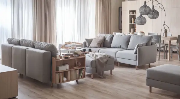 Jasne wnętrza inspiracje: przytulny salon z szarą sofą, drewnianymi meblami i zasłonami.