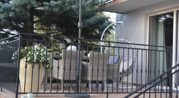 Taras nad garażem inspiracje: rattanowe meble, wiszący fotel i bujna zieleń tworzą przytulną przestrzeń do relaksu.