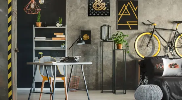 Nowoczesne ściany w pokoju młodzieżowym z betonową fakturą, ozdobione złotymi grafikami i czarnymi akcentami. Styl industrialny i rockowy.