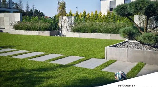 Nowoczesne płyty betonowe w ogrodzie tworzą ścieżkę przez trawnik. Aranżacje z betonowych elementów podkreślają piękno zieleni.