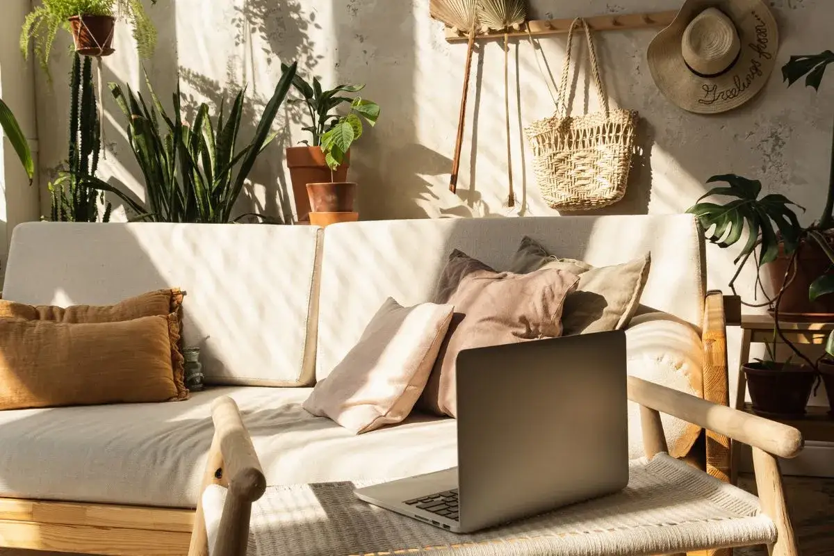 Słoneczny salon z kanapą, mnóstwem roślin i plecionymi dodatkami. Idealne wnętrza boho inspiracje do relaksu i pracy.