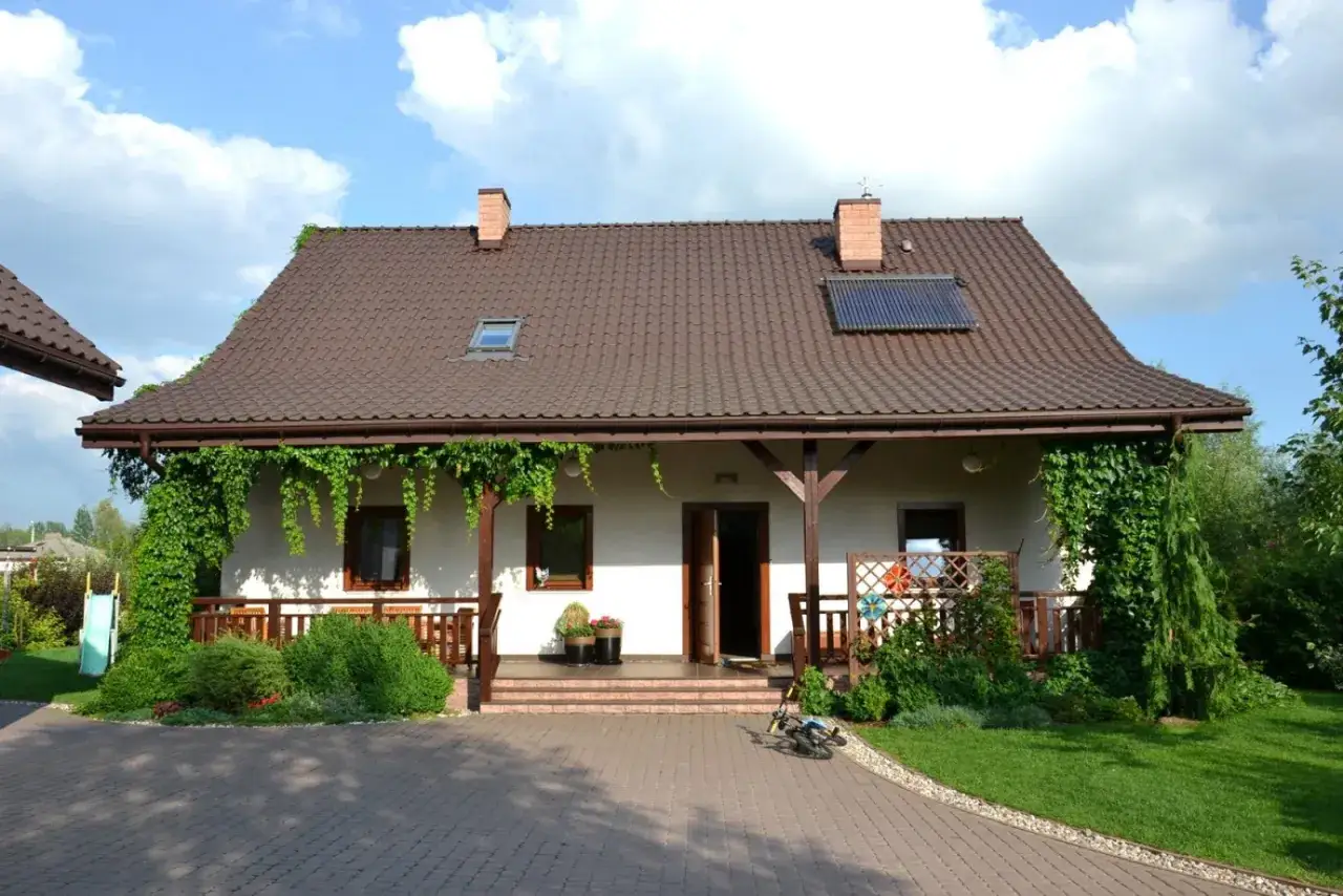 Urokliwe, stylowe domy wiejskie otoczone zielenią. Wjazd z kostki brukowej prowadzi do przytulnego ganku.