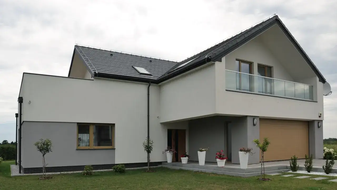 Nowoczesny dom z jasną elewacją, która podkreśla najmodniejsze kolory elewacji. Duże okna i szklana balustrada dodają elegancji.