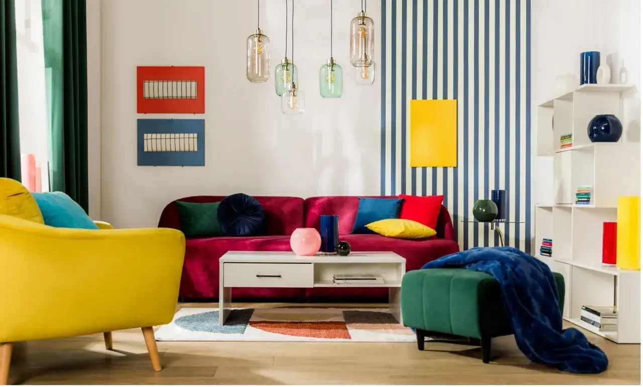 Salon w stylu Memphis: żółty fotel, bordowa kanapa, geometryczna tapeta i kolorowe dodatki tworzą radosną atmosferę.