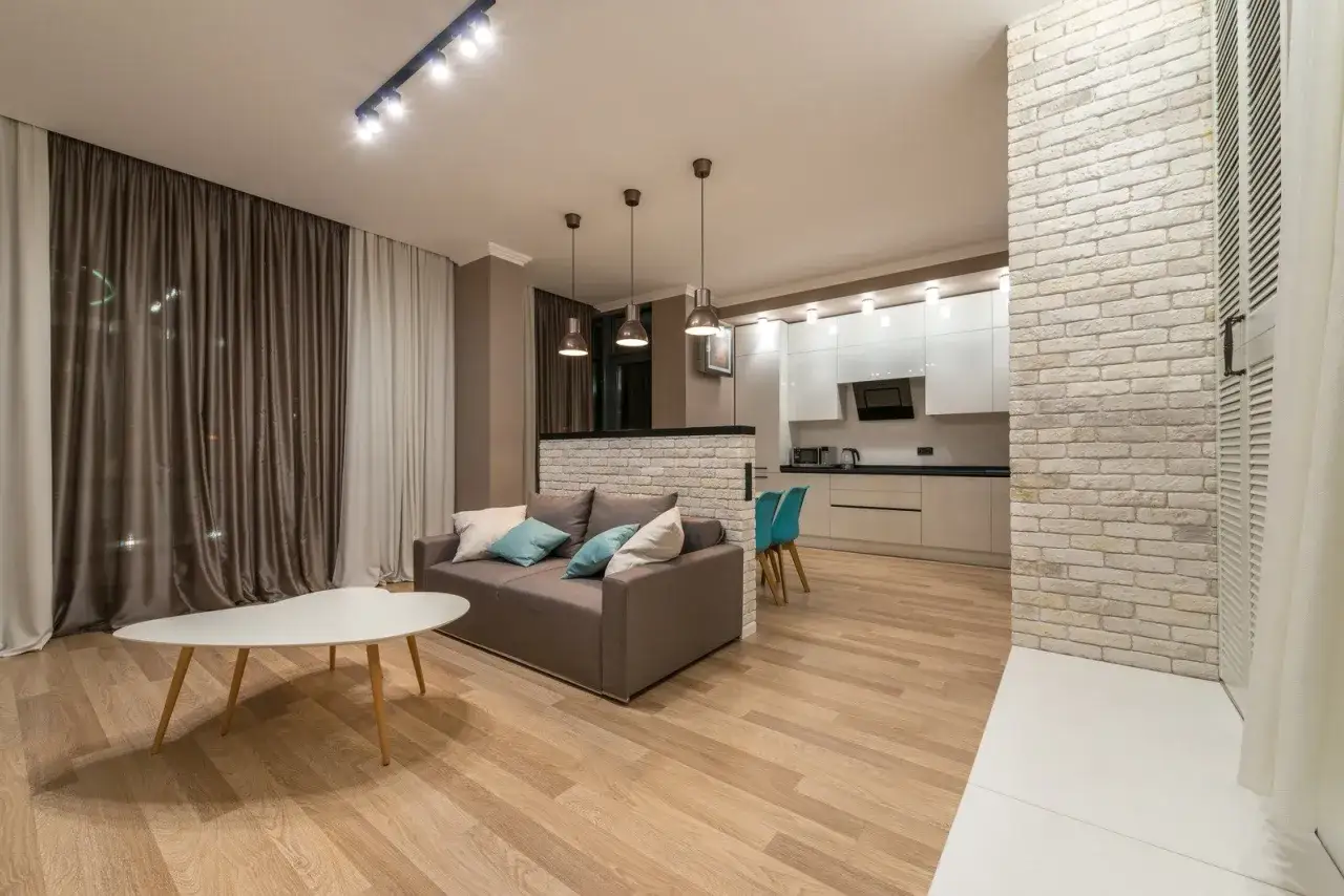 Nowoczesny projekt mieszkania 45m2: salon z sofą i stolikiem kawowym, aneks kuchenny z białymi meblami i turkusowymi krzesłami.