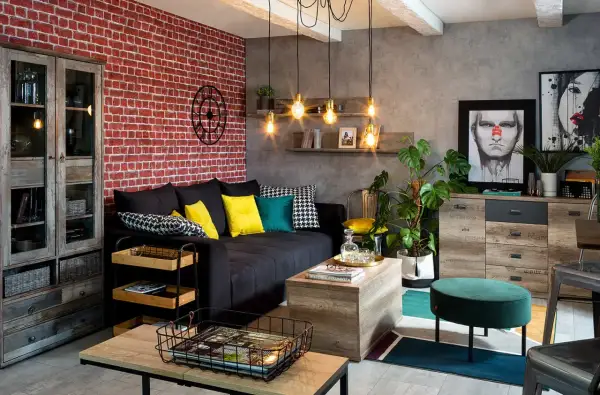 Męski pokój inspiracje: loftowy salon z ceglaną ścianą, czarną kanapą, drewnianymi meblami i industrialnymi lampami.