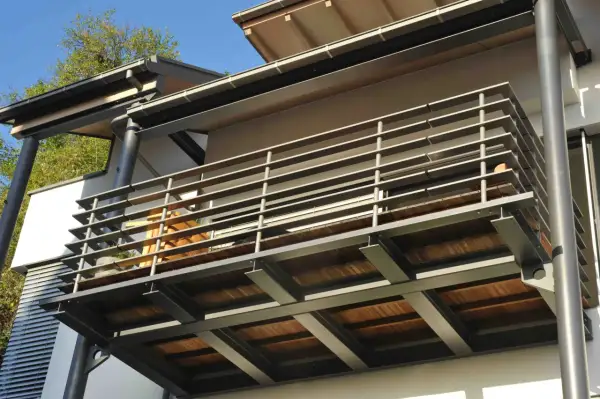Nowoczesne rodzaje balkonów: stalowa konstrukcja z drewnianym tarasem i metalową balustradą.