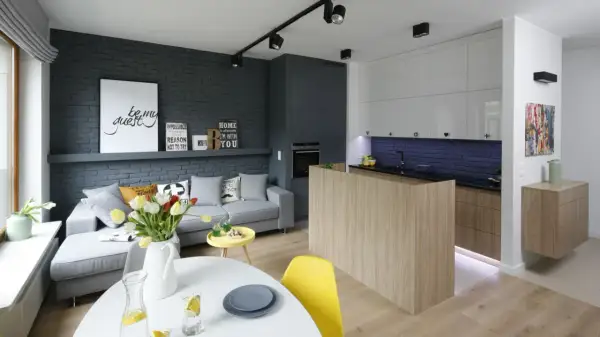 Nowoczesny salon z aneksem kuchennym w bloku, urządzony w stylu loftowym. Szara cegła, drewno i jasne meble tworzą przytulną przestrzeń.