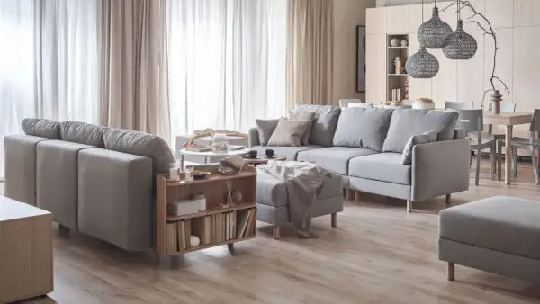 Jasne wnętrza inspiracje: przytulny salon z szarą sofą, drewnianymi meblami i zasłonami.