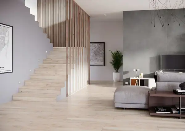 Nowoczesna klatka schodowa projekt z drewnianymi balustradami i subtelnym oświetleniem. Obok salon z szarą ścianą i wygodną sofą.
