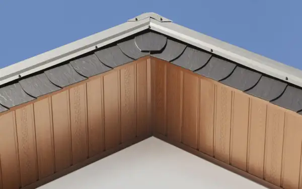 Drewniana podbitka dach dwuspadowy z szarymi dachówkami i metalowym wykończeniem, pod błękitnym niebem.